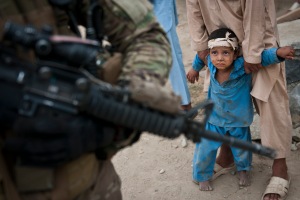 NANGARHAR PROVINCE, Afghanistan – An Afghan boy, who fell a few days ago, is held by his father as U.S. Army Pfc. Jonathan V. Bachtel, a forward observer from Burleson, Texas, assigned to Troop C, 3rd Squadron, 4th Cavalry Regiment, Task Force Raider, 3rd Brigade Combat Team, 25th Infantry Division, Task Force Bronco provides security during a patrol in Rodat District in eastern Afghanistan's Nangarhar Province, July 18. The boy is related to a wood worker who just received news that his business will receive a small business grant to help stimulate the economy and provide for his family. (Photo by U.S. Army Sgt. 1st Class Mark Burrell, 210th MPAD)